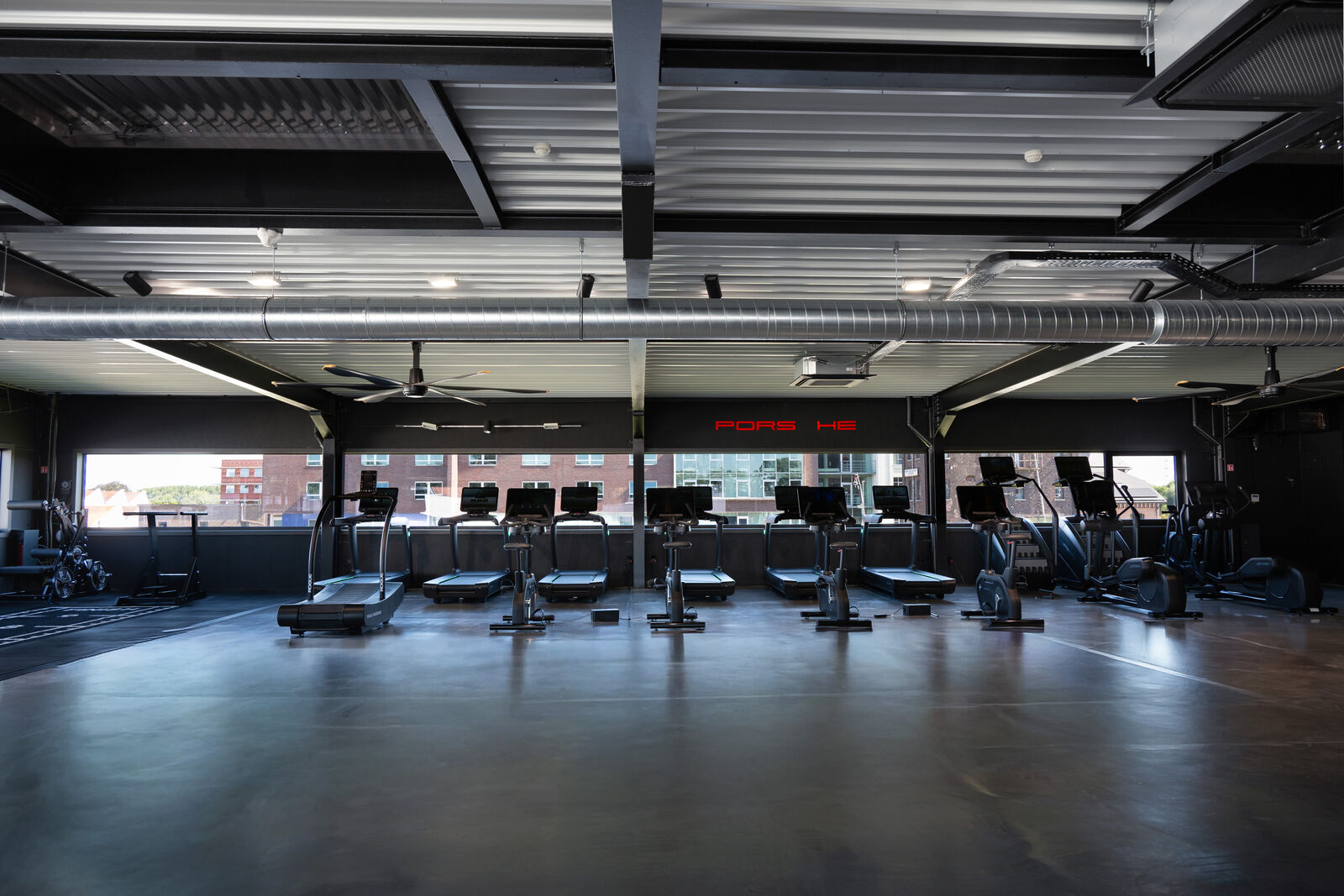 A row of treadmills and bikes looking outside